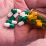 Green and white pills in a hand