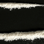 powder drug lined up on black background