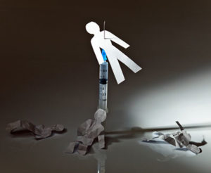 A paper figure stabbed with a syringe symbolizing heroin overdose